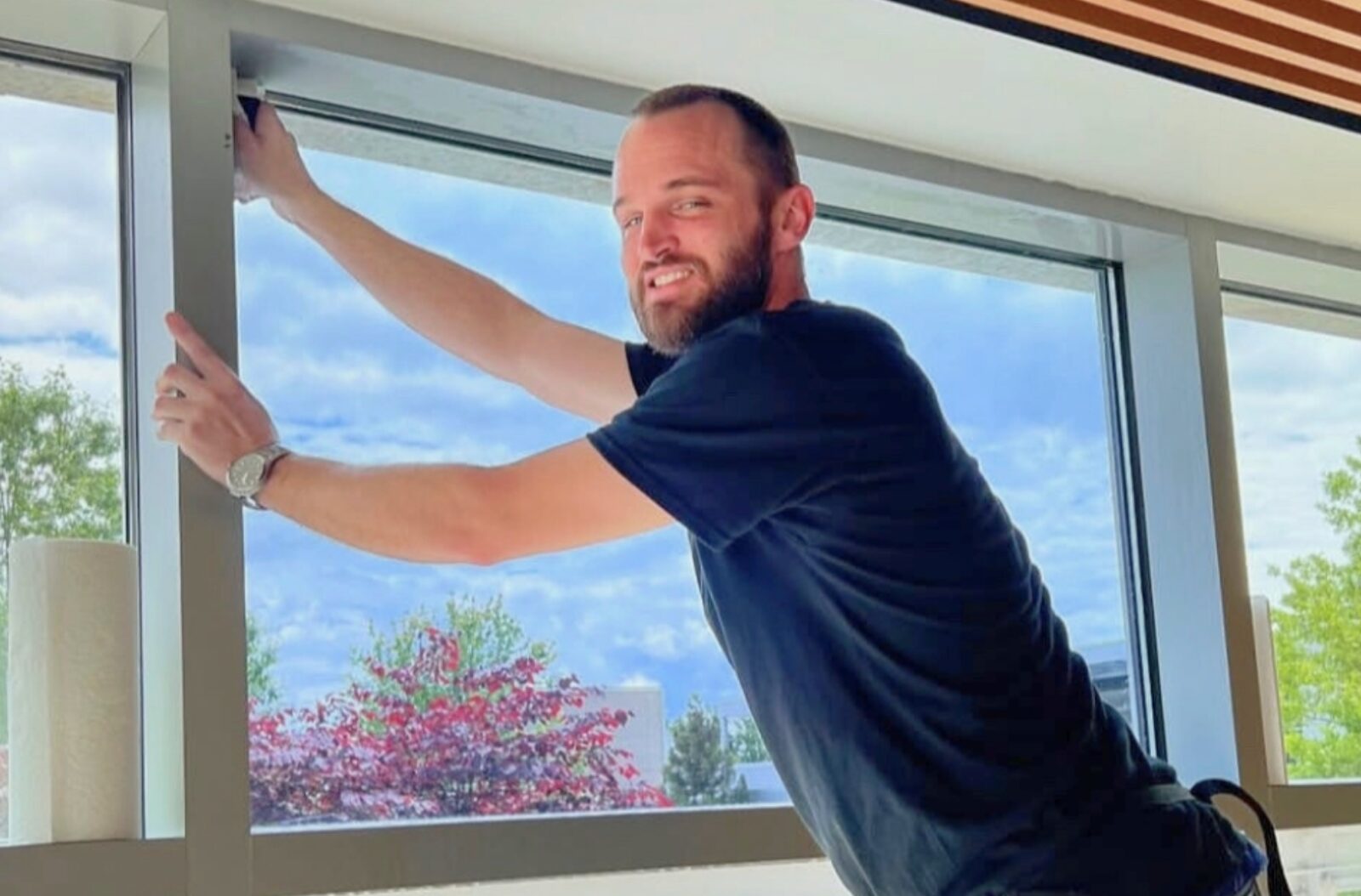Technician installing photochromic window film on a large commercial window to control glare and heat.