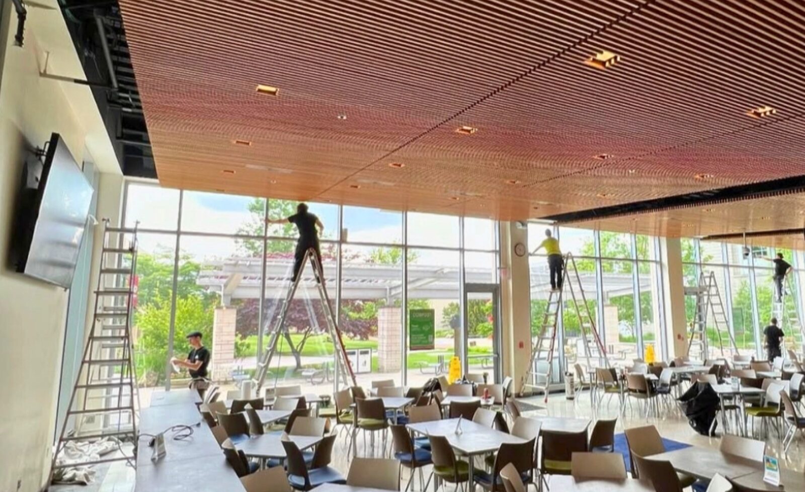 Team of installers applying window film to tall café windows for complete coverage.