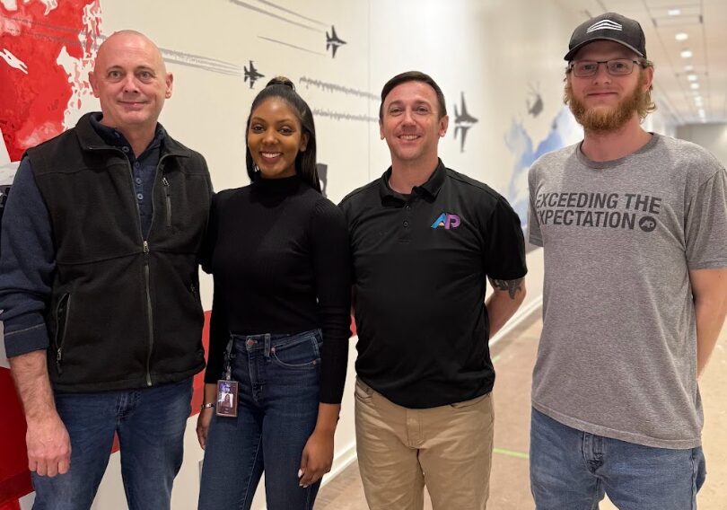 AP Corp team in front of aviation-themed mural highlighting the benefits of wall murals for offices.