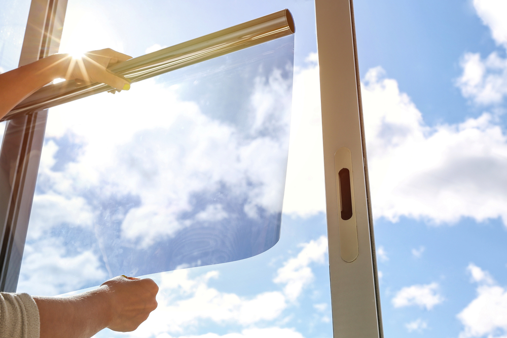 sun and glass A Photo of Installer Pulling out Window Film Summer Sky