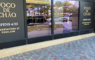 A storefront for Fogo de Chao features window film advertising the opening day.