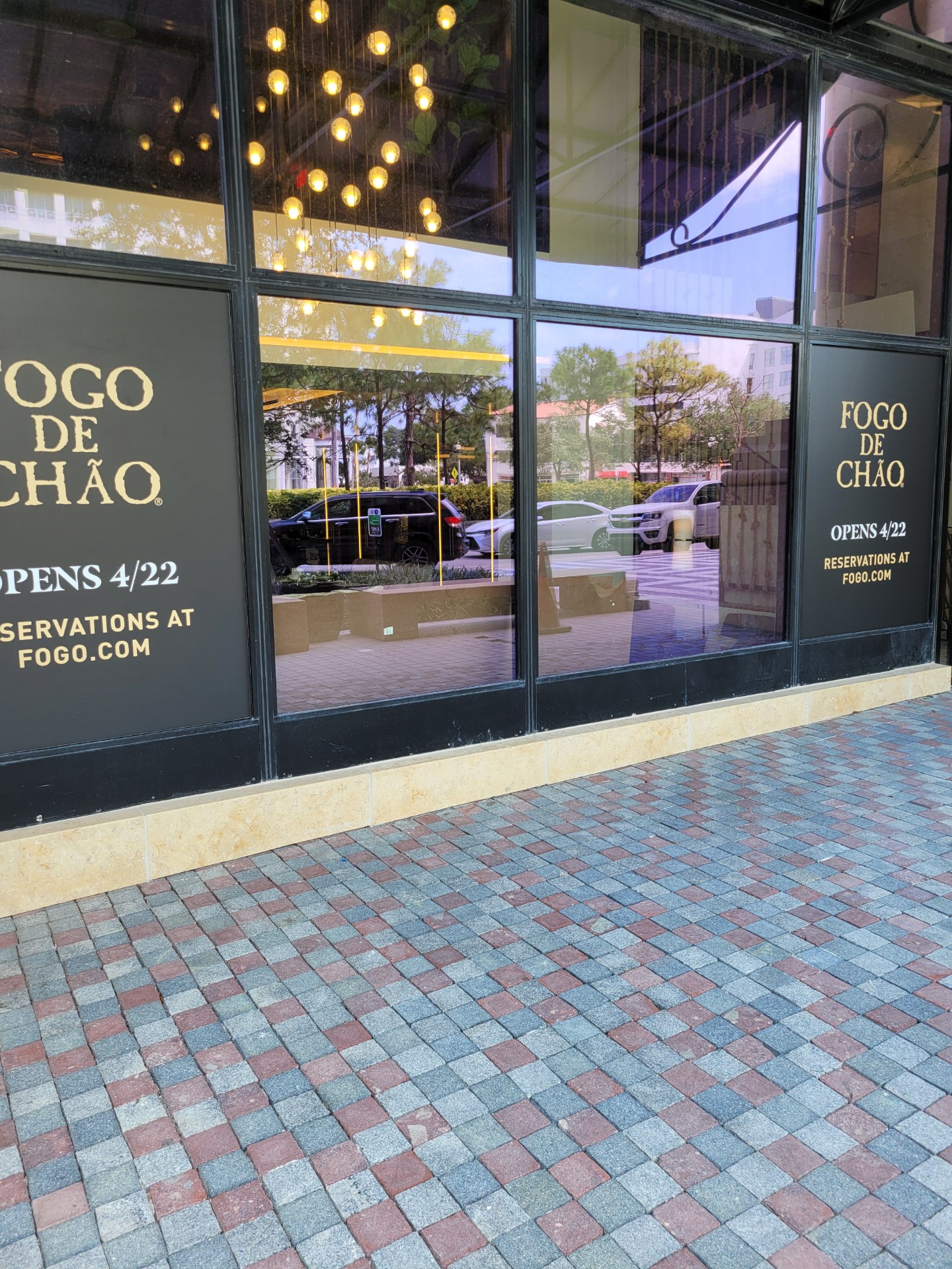 A storefront for Fogo de Chao features window film advertising the opening day.