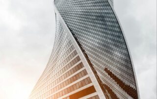 Sunlight reflects off the glass of a beautiful high rise featuring a curved construction.