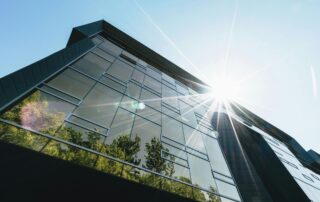 Exterior of a glass office building, trees reflected in the windows