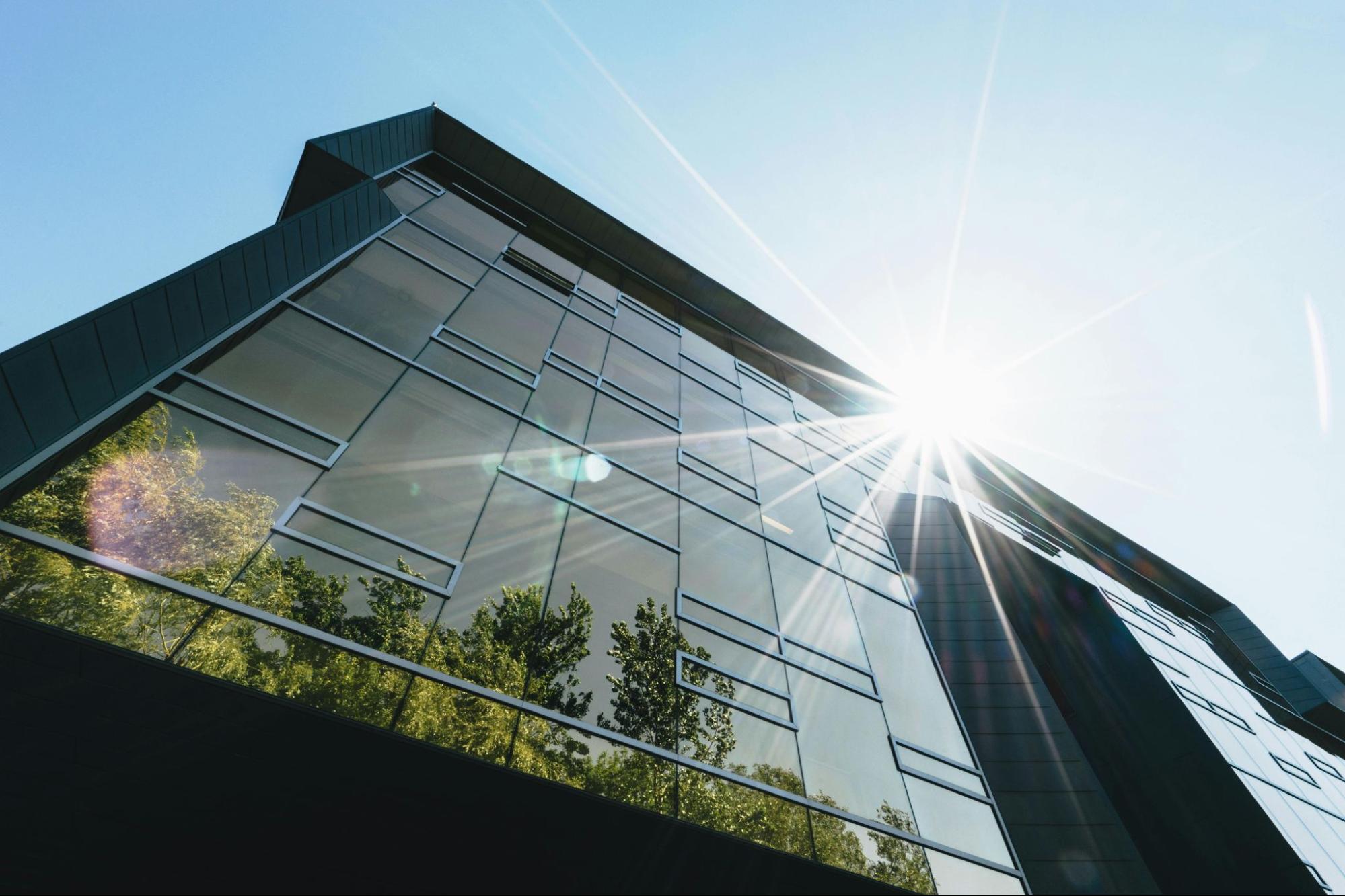 Exterior of a glass office building, trees reflected in the windows