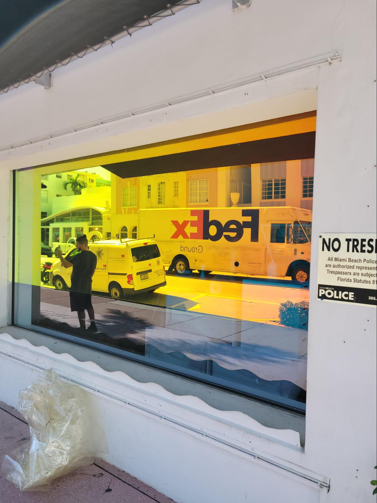 A store window with reflective tinted film installed reflecting the activity on the adjacent street.
