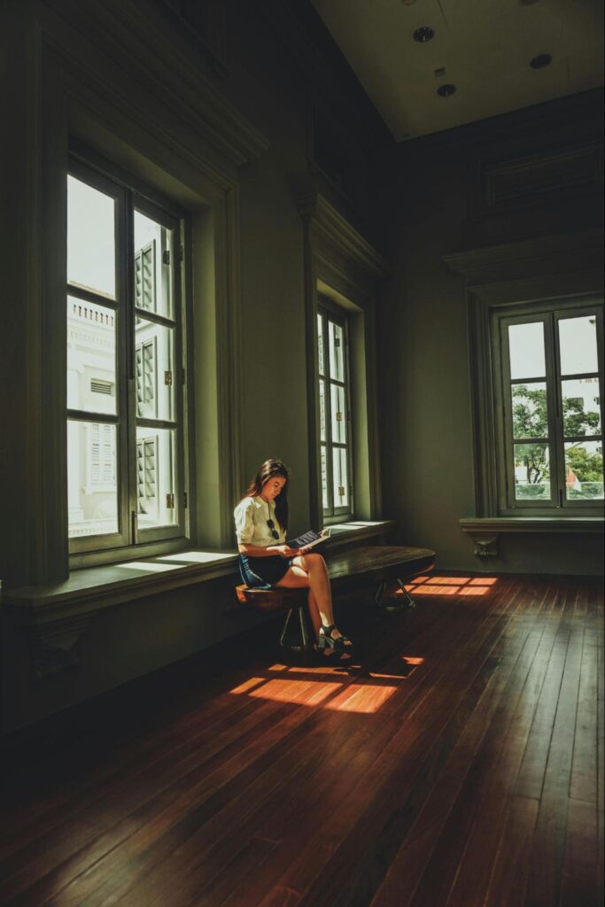 Woman Sitting in Large Room with Windows