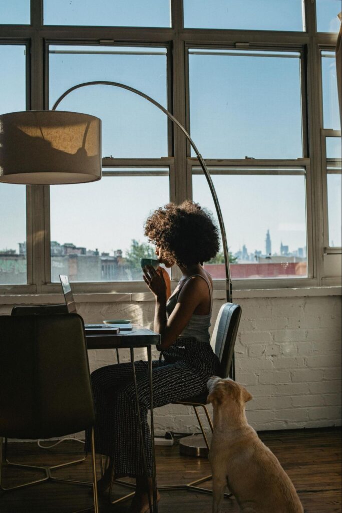 Woman Sitting at Table with Dog and City View