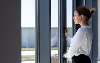 A woman standing near a window secured against break-ins.