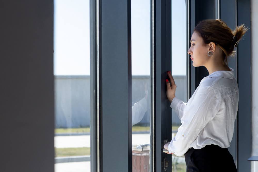 A woman standing near a window secured against break-ins.