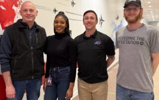 AP Corp team in front of aviation-themed mural highlighting the benefits of wall murals for offices.